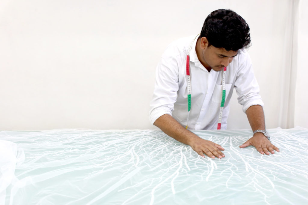 Quality checker checking a production piece to see if it matches the paper patterns, the quality of beading and materials is couture standard